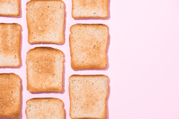 top view of rows of crispy toasts on pink surface