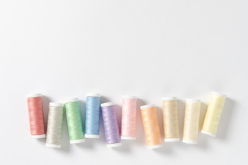 Colored thread coils on white background, sewing, place for text. Top view