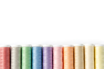 Multicolor thread coils on white background, sewing, place for text. Top view