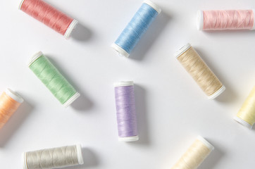 Multicolor thread coils on white background, sewing, pattern. Top view