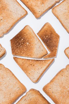 top view of heart shape made of grunchy toast with slices of bread around on white surface