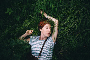 Relaxing redhead hipster girl is lying in the green grass. Processing under the film.