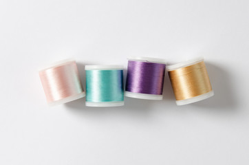 Color sewing threads on white background, top view
