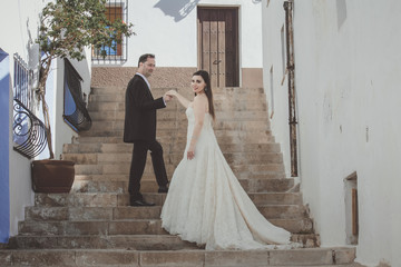Young couple on their wedding day, on a large stairway in a mediterranean village