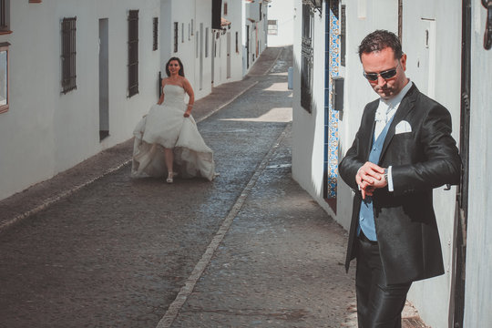 Young wedding couple in the street. The groom is waiting, the bride is running towards him