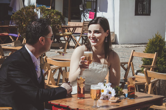 Young wedding couple on their wedding day, relaxing in a bar and having a beer