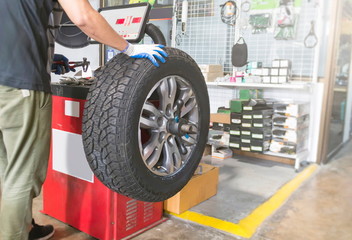 Mechanic balancing a car wheel on an automated machine at the garage.