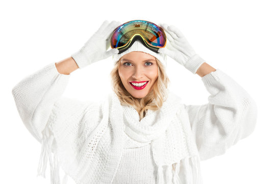 Beautiful young woman in winter clothes with ski goggles on head smiling and looking at camera isolated on white