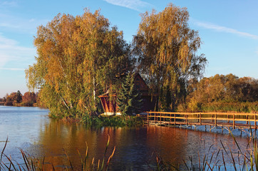 Scenic view of island with abandoned house and trees in the middle of the lake. Autumn morning...