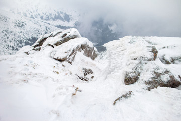 Fototapeta na wymiar Snowy mountains with deep ravine and rock cliffs
