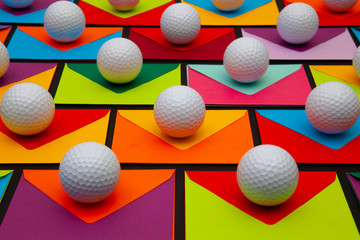 Composition with colored envelopes and golf balls on the table.
