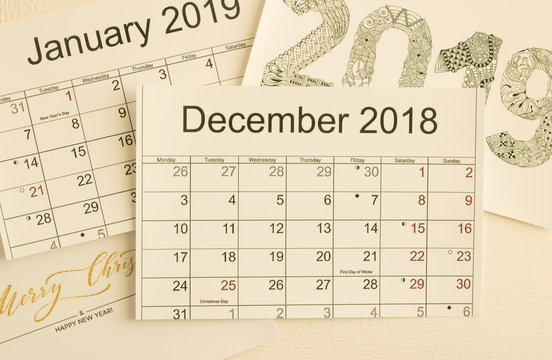 Close-up: calendar December 2018 is on top of images of calendar January 2019 and holiday greetings. Top view. Concept: Merry Christmas and Happy New Year holidays.