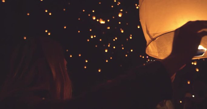 Happy young woman holding lit paper lantern at night during lantern festival 