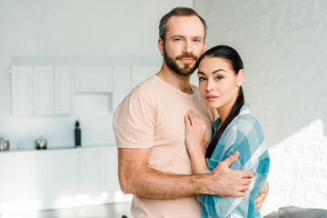 Fototapeta premium portrait of beautiful couple embracing and looking at camera at home
