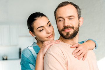 portrait of happy wife embracing smiling husband at home