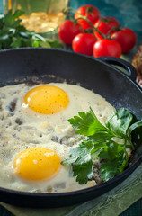 Fried egg in a frying pan with cheese and greens.