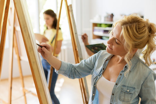 art school, creativity and people concept - woman with easel drawing at studio - Powered by Adobe