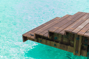 travel, tourism, vacation and summer holidays concept - wooden pier with stair in sea water in french polynesia