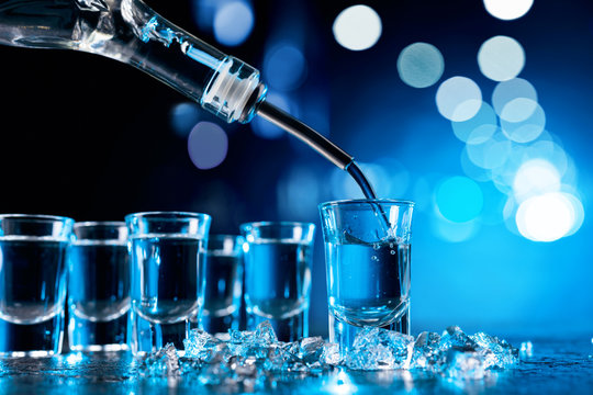 Vodka poured into a glass lit with blue backlight.