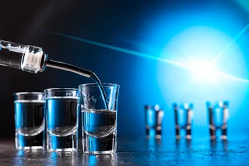 Photo sur Plexiglas Bar La vodka versée dans un verre éclairé par un rétroéclairage bleu.