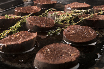 home made black pudding with oil and thyme in a pan