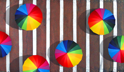 People walking with a colorful umbrellas on a pedestrian crossing. Happiness and peace concept...