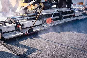 Straßenbau - Asphaltmaschine legt neue Fahrbahnbeschichtung, Nahaufnahme