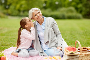 family, leisure and people concept - happy grandmother and granddaughter having picnic at summer...