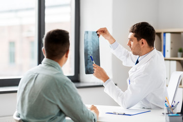 medicine, healthcare and people concept - doctor showing x-ray to patient at medical office in...