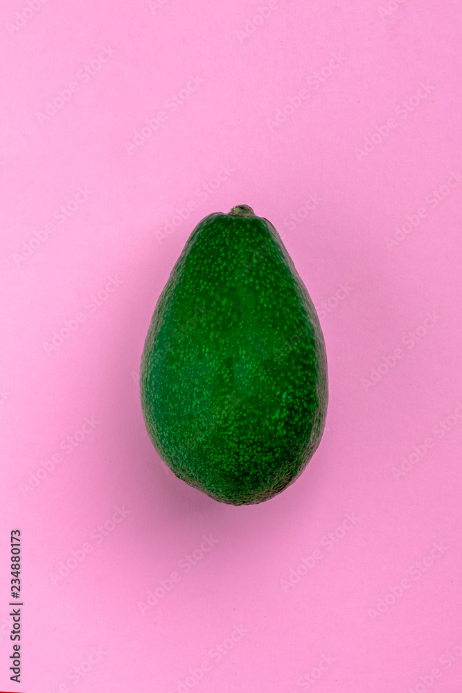 Wall mural vertical creative layout of bright ripe green avocado on a pink textured design cardboard. vertical 