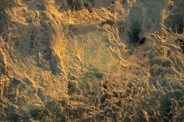 Sea waves creating abstract design with golden hour light