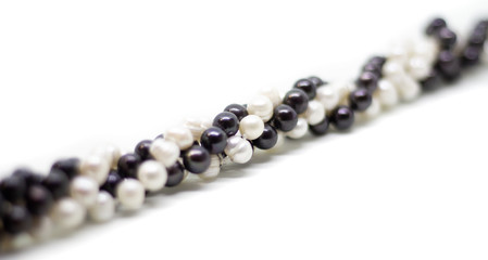 Two strands of white and black pearls intertwined on white background isolated