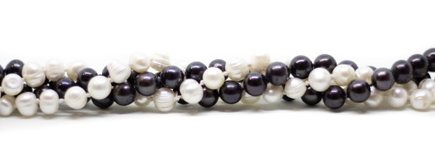 Two strands of white and black pearls intertwined on white background isolated