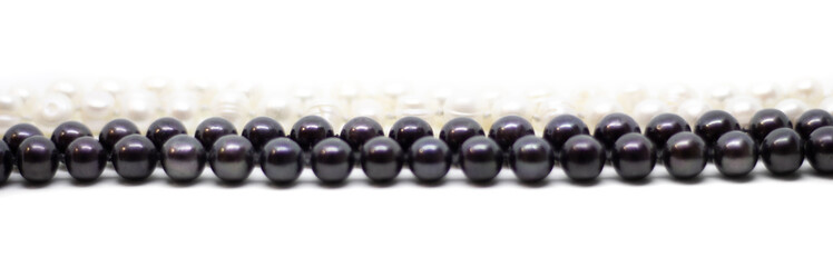 Two strands of white and black pearls intertwined on white background isolated