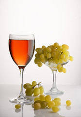 glass of wine and a bunch of ripe grapes on white background