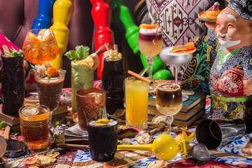 Whiskey-cola cocktail, mojito-cocktail, orange cocktail, strawberry cocktail in glass glasses with straws. Bar accessories: shaker, spoon, spices on a wooden stand