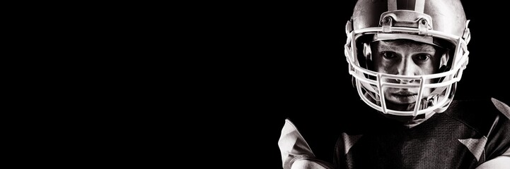 American football player in helmet standing against black