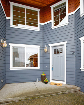 Main entrance of grey two story tall house exterior.