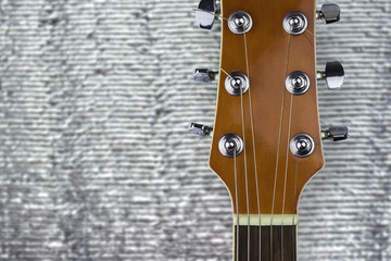 Headstock of a classical guitar over silver background