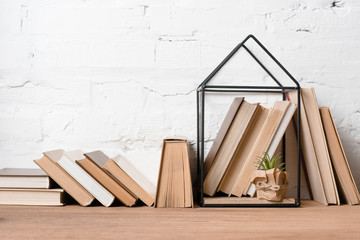 books and green potted plant in house model decoration on wooden table