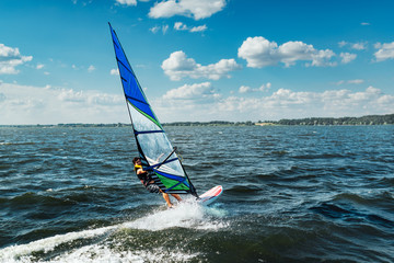 Naklejka premium the man athlete rides the windsurf over the waves on lake