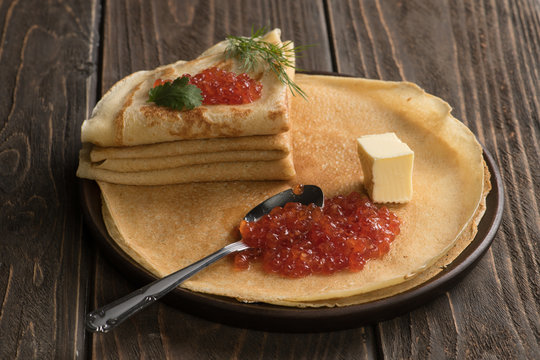 Russian pancakes with red caviar, steel spoon and piece of butter