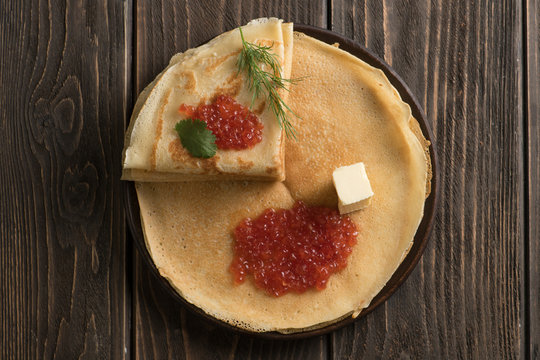 Top view of russian thin pancakes with red caviar and piece of butter