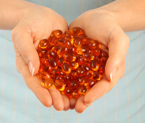 WOMAN HOLDING VITAMIN OIL CAPSULES