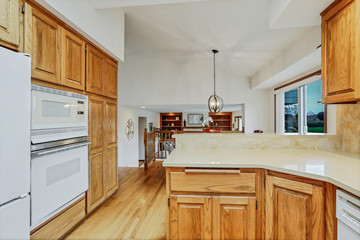 Open large kitchen interior with vaulted ceiling and white appliances.