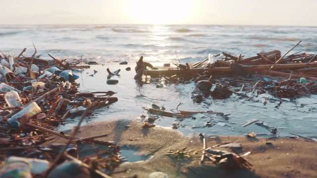 Plastic bottles, bags and other garbage dumped on black beach and in ocean. Environmental pollution problem concept
