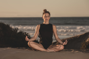 Naklejka na ściany i meble Meditating woman in bodysuit on beach