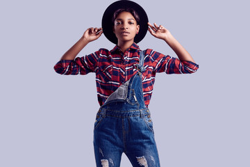 Elegant black hipster girl with short hair in a plaid shirt and denim overalls.