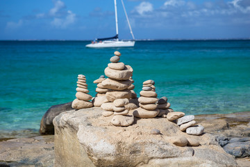 Stacks of stones in balance at a beach with yacht on a background