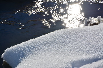Snowy crystals in the sun with water in the background